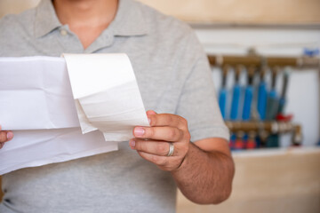 Man holding repair bill with pipes in his background