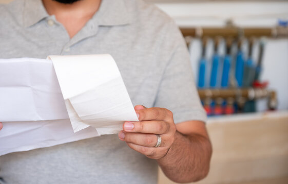 Man holding repair bill with pipes in his background