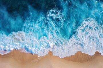 Fototapeta premium Aerial view of ocean waves crashing onto a sandy shore.