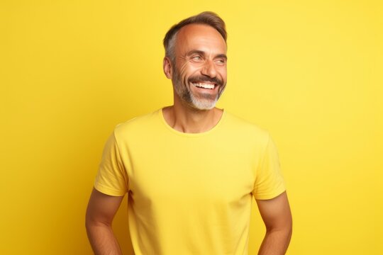 Portrait of happy mature man in yellow t-shirt on yellow background