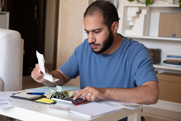 young bearded male callculating living costs in living room