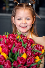 A little girl with a big bouquet of tulips. Beautiful bunch of flowers as a gift for Valentine's Day, Women's Day 8 March, birthday, holiday
