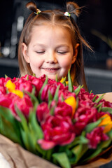 A little girl with a big bouquet of tulips. Beautiful bunch of flowers as a gift for Valentine's Day, Women's Day 8 March, birthday, holiday