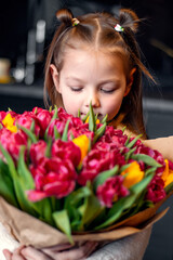A little girl with a big bouquet of tulips. Beautiful bunch of flowers as a gift for Valentine's Day, Women's Day 8 March, birthday, holiday