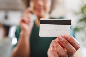 A cheerful mature woman is making an online purchase or payment, utilizing a credit card and a laptop computer. Online banking concept