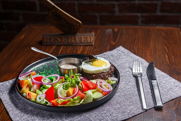 salad nicoise with vegetables and egg, on a plate, tablecloth on the table, dark and moody, top new