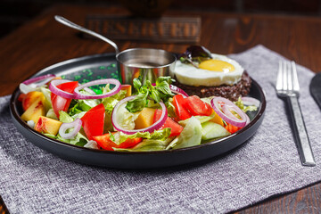 salad nicoise with vegetables and egg, on a plate, tablecloth on the table, dark and moody, top new