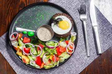 salad nicoise with vegetables and egg, on a plate, tablecloth on the table, dark and moody, top new