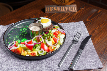 salad nicoise with vegetables and egg, on a plate, tablecloth on the table, dark and moody, top new