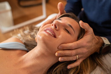 A woman enjoys a craniosacral therapy session, experiencing relaxation with a gentle head massage.