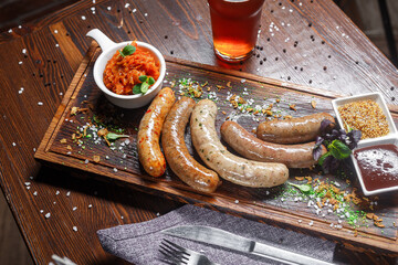 Small German boiled sausages, Nuremberg fried, on a plate, sauces and beer, dark and moody, top new