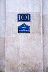 In the background of a cement wall, a plaque with the name of the Avenue des Champs-Elysées street in Paris, France. - obrazy, fototapety, plakaty