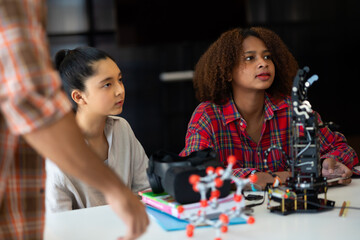 Happy african american girl and diverse teens students group building robotic  hand using laptop computer. Building And Learning To Program electric Robot. STEM coding engineering class.
