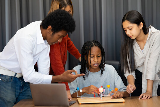 Group diverse students boy and girls looking at models solar system in an astronomy class. Dlectric planet models. chemistry class. Diverse student sci workshop