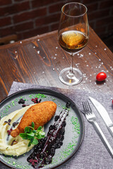 Chicken Kiev cutlet with mashed potatoes, on a plate, croutons and a glass of wine, dark and moody, top new