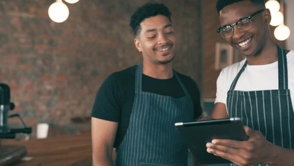 Cashier, people or barista on tablet for cafe teamwork, social media ideas and inventory or restaurant management. Young men or small business owner training on digital technology at a coffee shop - Powered by Adobe