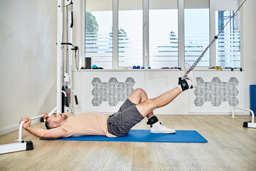 side view of sportive man lying down on fitness mat during recovery training in kinesio center