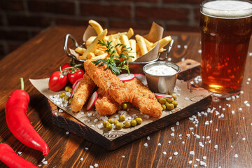 French fries, cheese sticks on a wooden board, beer and white sauce, dark and moody, top new