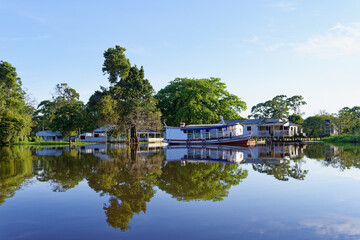 Wooden houses on stilts reflecting in the Amazon River, Amazonas state, Brazil