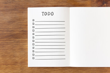 Notebook with to-do list on wooden desk, overhead angle
