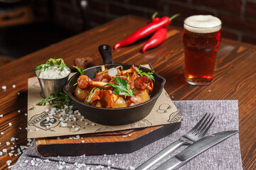 Fried potatoes with mushrooms and chicken in a cast iron frying pan, dark and moody, top new