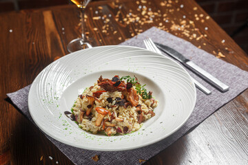 Risotto dish on a white plate and a glass of wine, dark and moody, top new