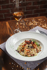 Risotto dish on a white plate and a glass of wine, dark and moody, top new