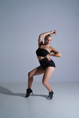 Female dancer in black shorts and top dancing in high heels. Young woman posing and showing body...