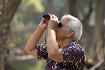 Adventurous senior man using binoculars