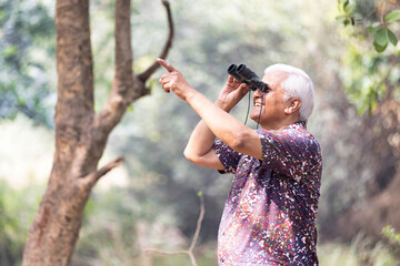 Adventurous senior man using binoculars