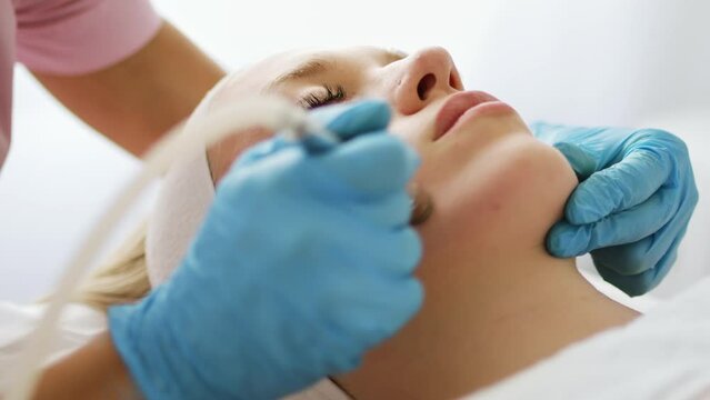 Beautician cosmetologist makes a procedure Microdermabrasion peeling of the face skin. Hardware cosmetology in clinic salon for client. Diamond face clean.	