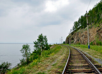Jezioro Bajkał, Rosja. Brzeg jeziora z kamienistą plażą, tory kolejowe, łodzie, pomosty w wodzie.