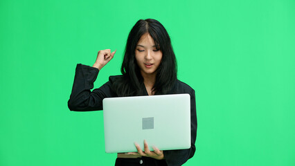 A girl in black clothes, on a green background, close-up, with a laptop