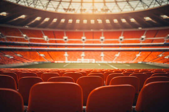 Empty football stadium with red seats, green grass and modern architecture.