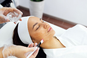 Naklejka premium Beauty master applies a rejuvenating mask to the clients face.
