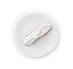 eclair with meringue on white plate top view