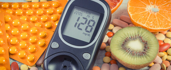 Glucometer for checking sugar level, fresh fruits and medical pills. Choice between eating fruits...