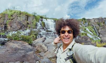 Naklejka premium exultant traveler takes selfie with waterfall in the background