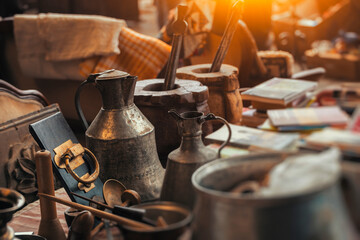 Vintage metal pitcher, vintage mortars, old door knob , old books on the countertop in sunday flea market. Details from antique bazaar.