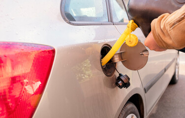 A man filling the fuel tank of his car with diesel fuel from the jerry can as there is no fuel at the petrol station, close up. The fuel crisis is continue - obrazy, fototapety, plakaty