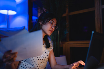 Late-night freelancer, Dedicated Asian woman working overtime on laptop computer, meeting deadlines...