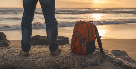 Bearded Man with backpack relaxing alone on the seaside on hot sunny day at sunset. Travel ...