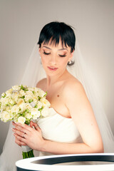 Beautiful bride with fashion wedding hairstyle - on white background.Closeup portrait of young gorgeous bride. Wedding. Studio shot.Beautiful bride portrait with veil over her face