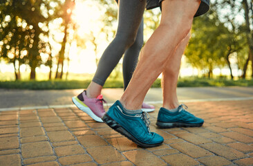 Heathy and active lifestyle. Close up of male and female legs in blue and pink sneakers jogging on...