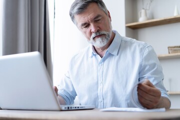 Man working on laptop from home. Counting financial data.
