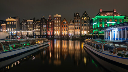 Medieval houses and cruise boats at the Damrak in Amsterdam the Netherlands by night