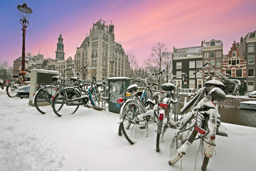 Naklejka premium Snowy city Amsterdam in the Netherlands in winter at sunset