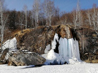 Beautiful landscape of frozen waterfall on the river, early spring in nature, stream streams turned into ice.
