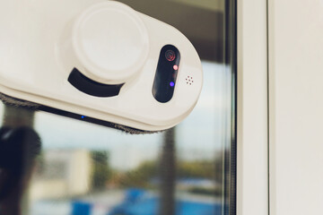 Vacuum cleaner robot cleaning window in high building outdoor.