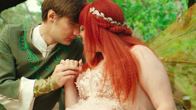 Young couple in people love. Romantic man and pixie woman sits hugs on tree. Themed wedding art fantasy family. Fairy woman in long pink dress bright golden wings. Prince king guy elf green costume
